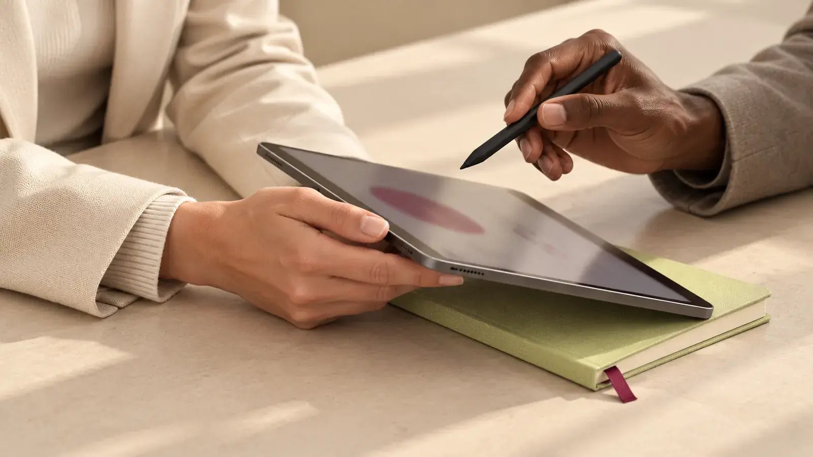 Hände mit Tablet und Stift auf einem Notizbuch